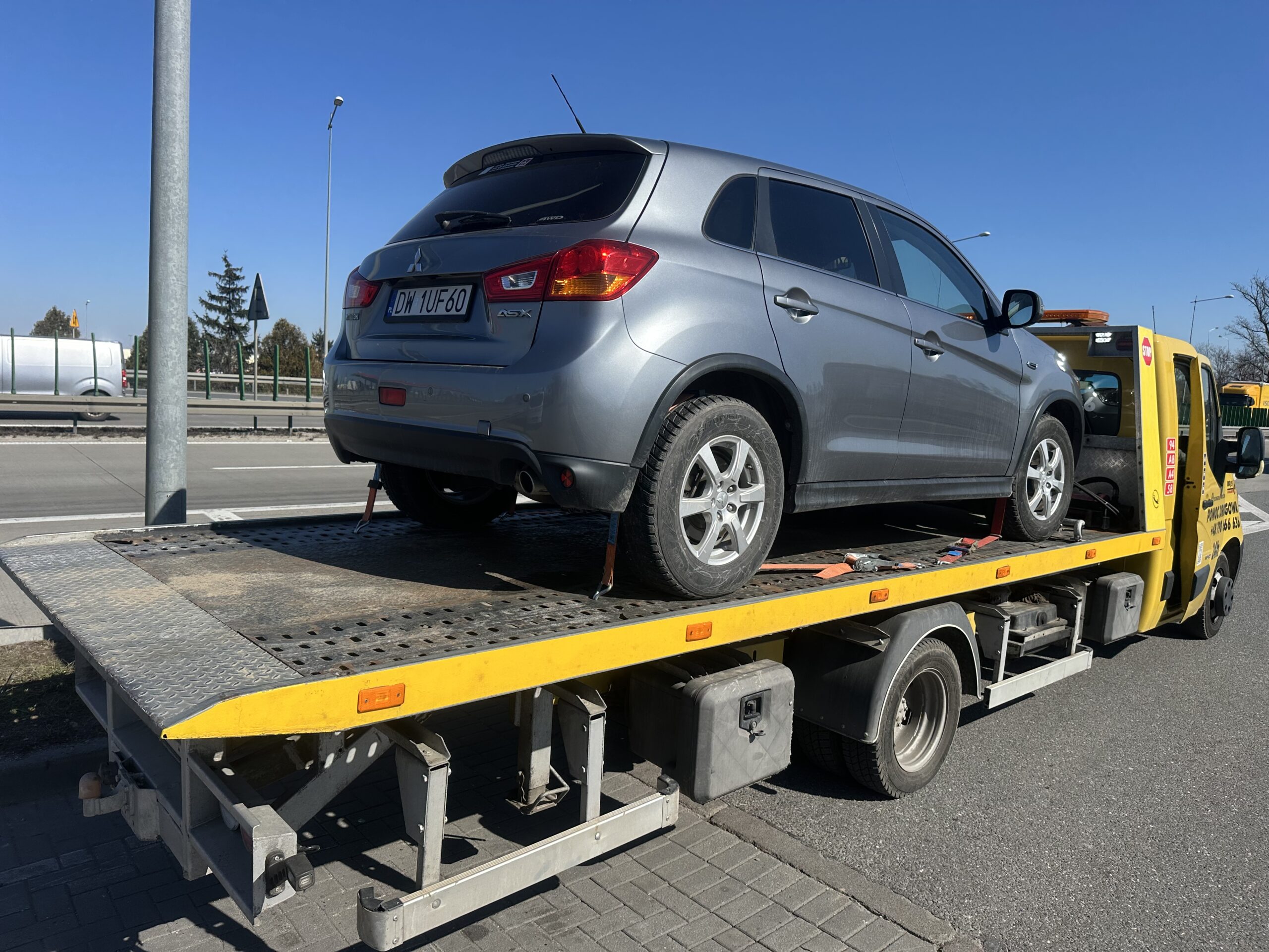 Transport pojazdu lawetą w dzień na drodze ekspresowej